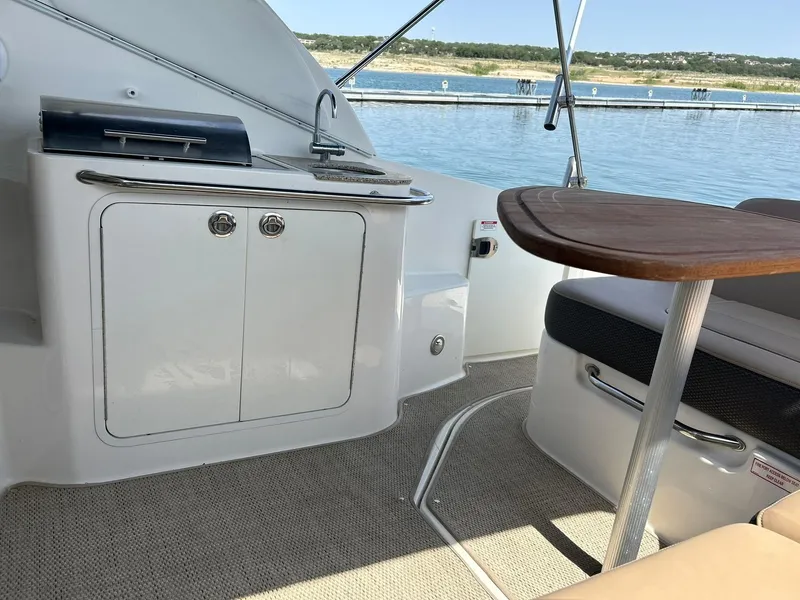 Slide: The Image of 2017 Sea Ray 280 Sundancer interior with kitchenette and seating, overlooking serene water. - 42