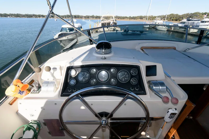 Slide: The Image of Helm of 1990 Fleming 50 yacht with steering wheel and instrument panel, docked by a serene lake. - 11