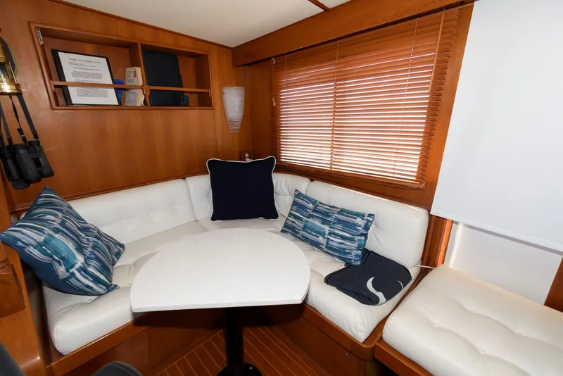 Slide: The Image of Cozy seating area in a 1990 Fleming 50 yacht with white cushions and wooden accents. - 25
