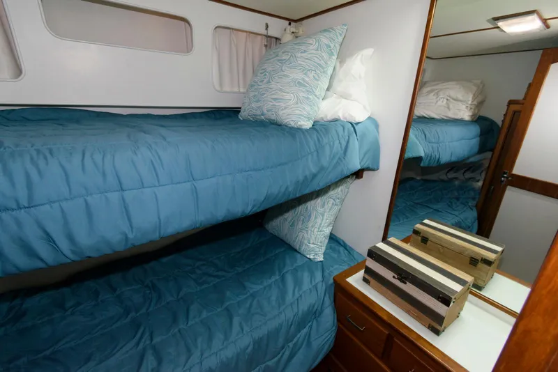 Slide: The Image of Bunk beds in a 1990 Fleming 50 yacht cabin with blue bedding and wooden accents. - 30