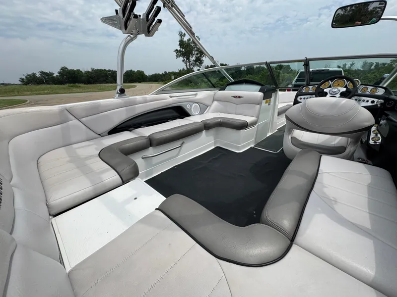 Slide: The Image of 2006 MasterCraft X30 boat interior with gray and white seating, open layout, and dashboard view. - 13