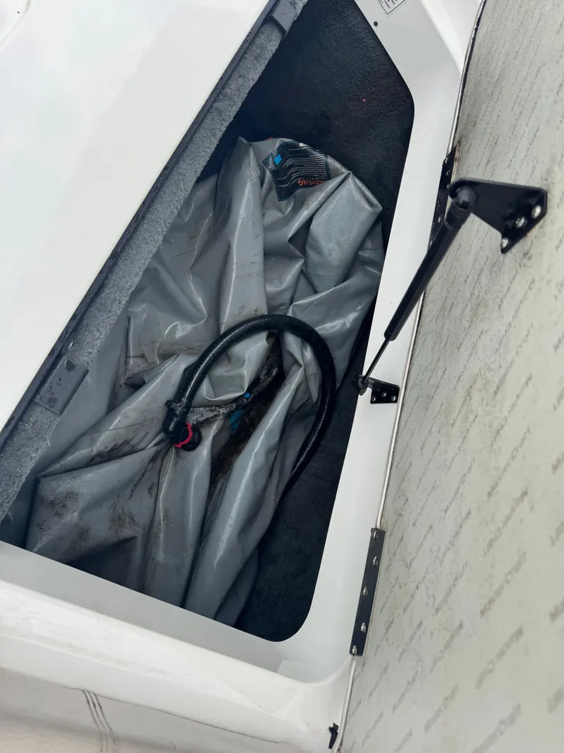Slide: The Image of Storage compartment in a 2006 MasterCraft X30 boat with a hose and cover. - 19