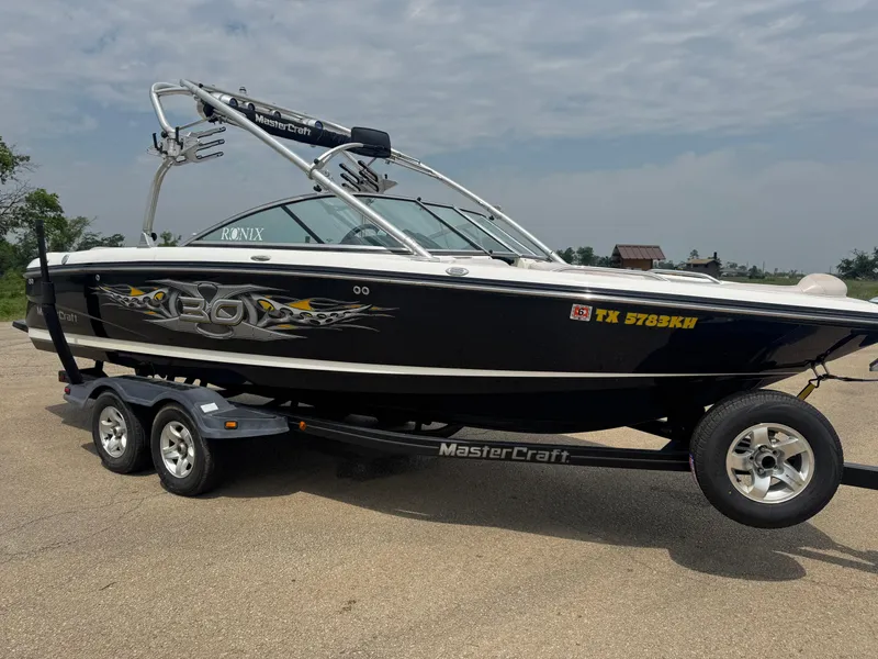Slide: The Image of 2006 MasterCraft X30 boat on trailer, black with graphics, parked outdoors. - 4