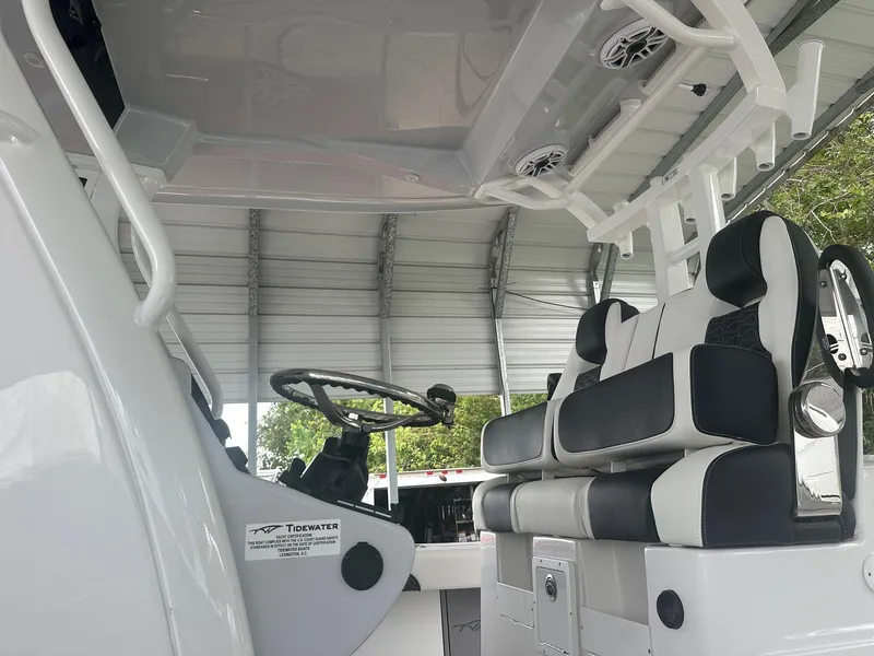 Slide: The Image of 2025 Tidewater 3100 Carolina Bay boat interior with steering wheel and seating under a canopy. - 10