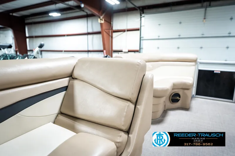 Slide: The Image of 2016 Bennington 20 SLMX pontoon boat interior with beige seating in a showroom. - 23