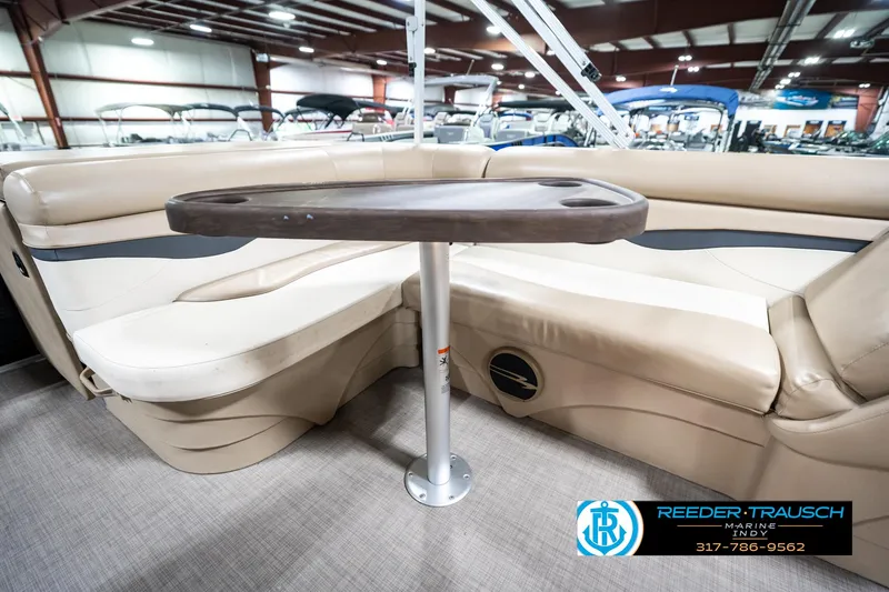 Slide: The Image of 2016 Bennington 20 SLMX boat interior with beige seating and a central table. - 25