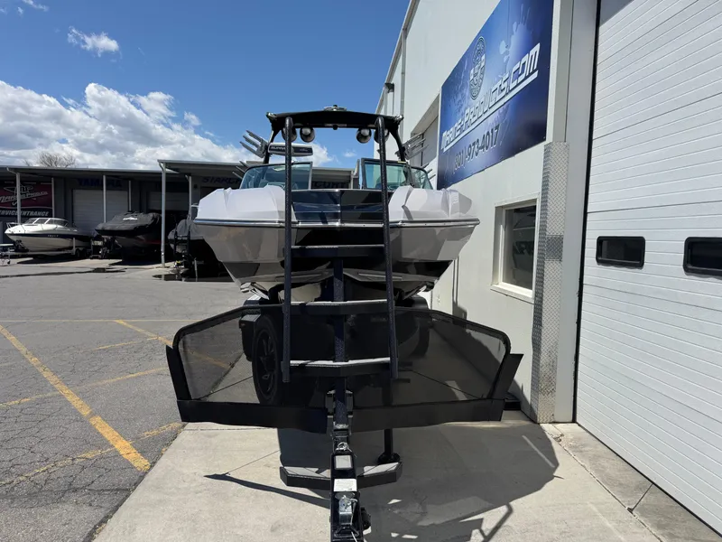 Slide: The Image of 2020 Supra SE550 boat parked outside a dealership under a clear blue sky. - 2