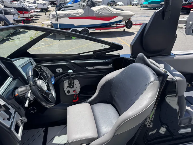 Slide: The Image of 2020 Supra SE550 boat interior with steering wheel and seating, docked among other boats. - 5