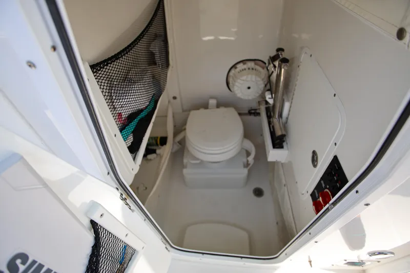 Slide: The Image of 2019 Sea Hunt Ultra 255 SE boat interior with compact marine toilet and storage. - 17