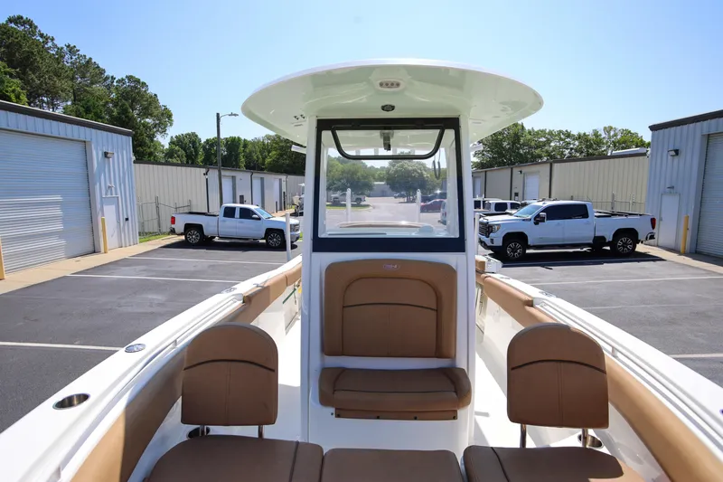 Slide: The Image of 2019 Sea Hunt Ultra 255 SE boat with tan seating, parked near industrial buildings. - 20