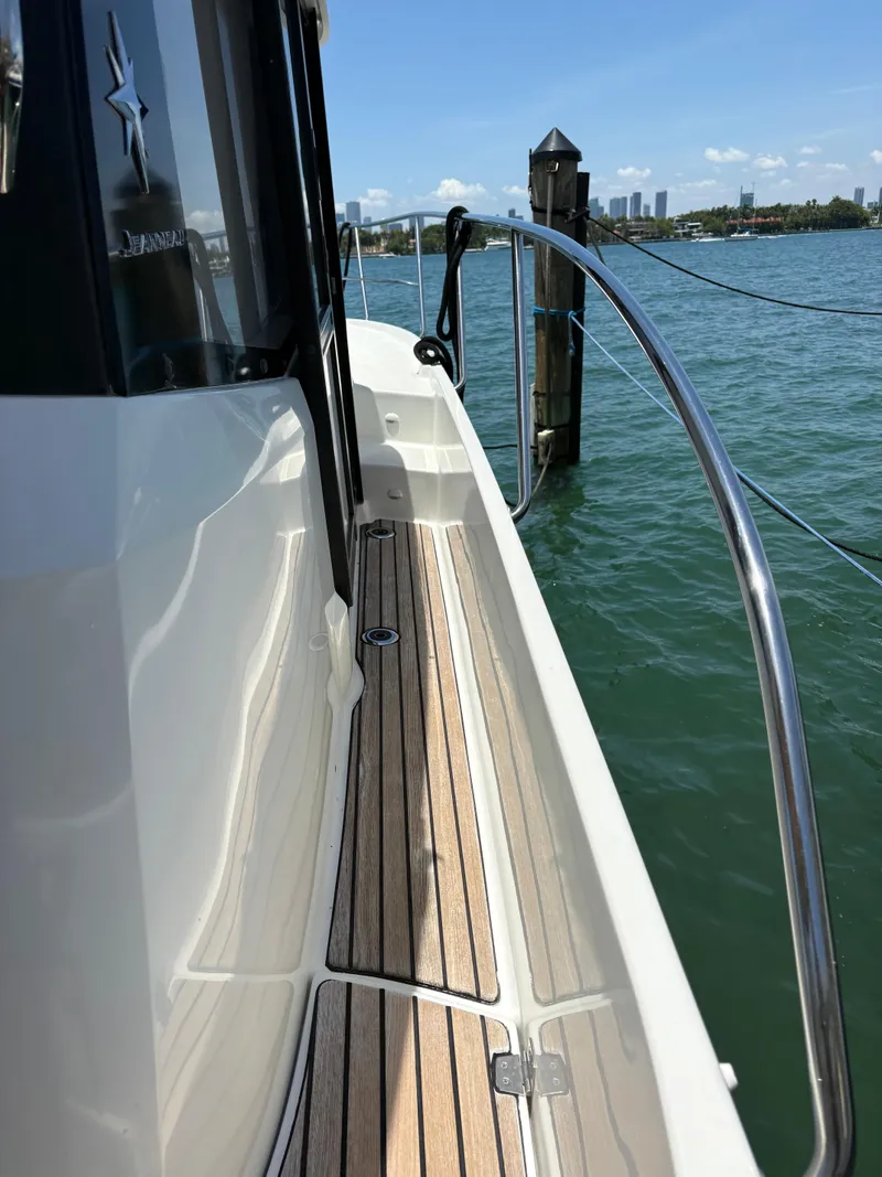 Slide: The Image of 2018 Jeanneau Merry Fisher 855 boat with teak deck, docked by the water. - 8