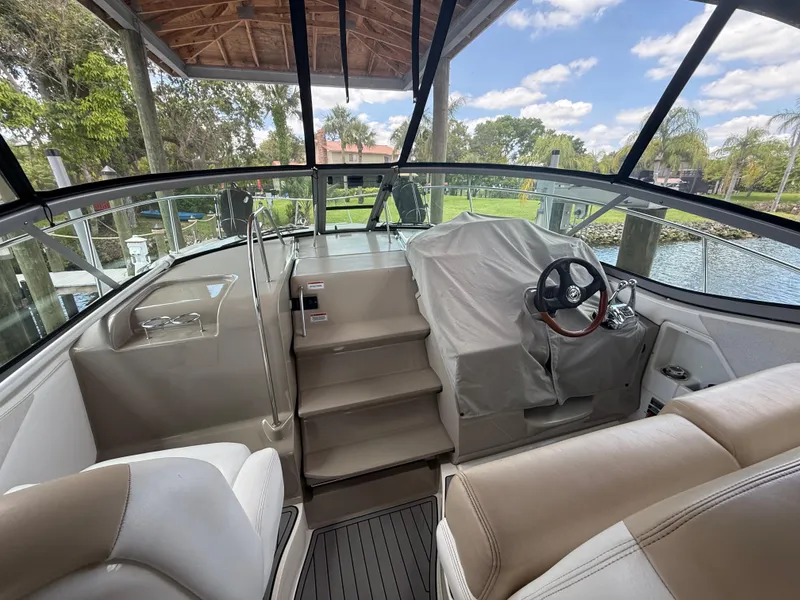 Slide: The Image of 2008 Sea Ray 330 Sundancer cockpit with covered helm, beige seating, and waterfront view. - 12