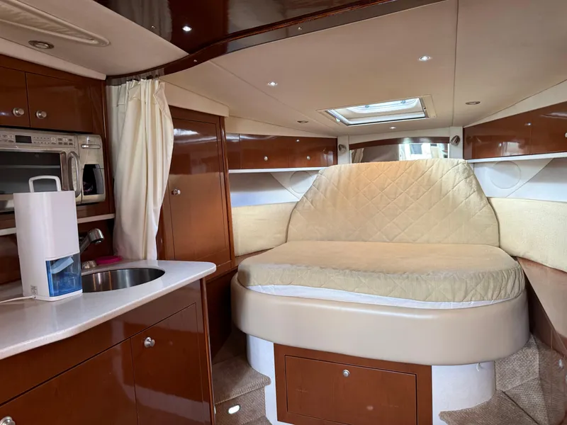 Slide: The Image of 2008 Sea Ray 330 Sundancer cabin interior with bed, kitchenette, and wood finish. - 30