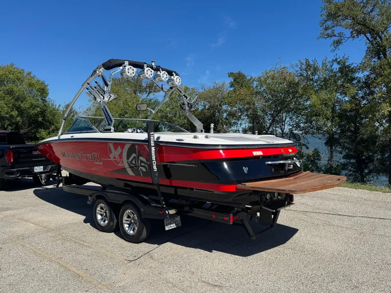 Slide: The Image of 2008 MasterCraft X45 boat on trailer, red and black design, parked near a lake. - 10