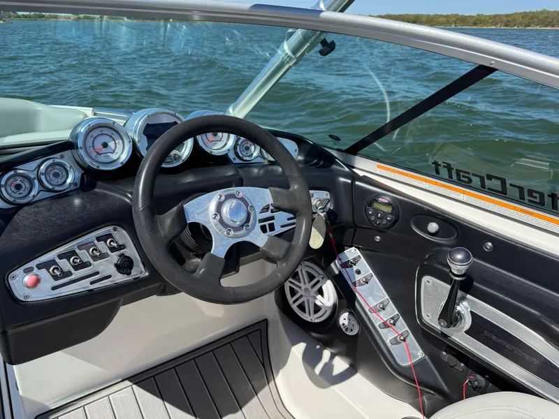 Slide: The Image of 2008 MasterCraft X45 boat dashboard with steering wheel and controls on a lake. - 21