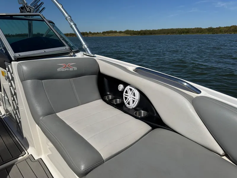 Slide: The Image of 2008 MasterCraft X45 boat interior with gray seating and cup holders on a lake. - 22