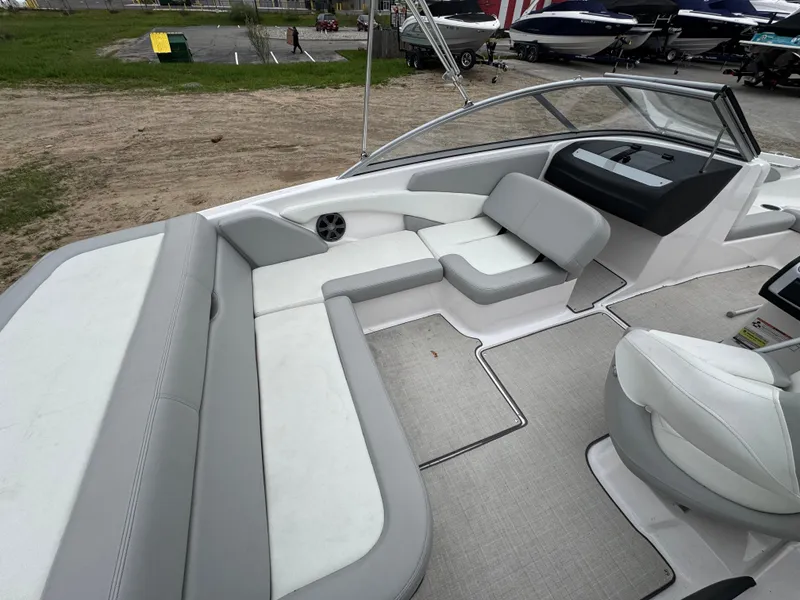 Slide: The Image of 2021 Regal 1900 ES boat interior with gray and white seating, docked outdoors. - 8