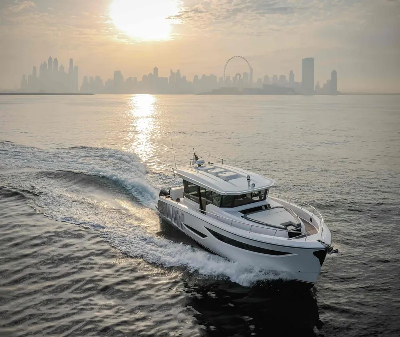 Slide: The Image of Oryx 47 LX yacht cruising at sunset with city skyline in background, 2025 model. - 2