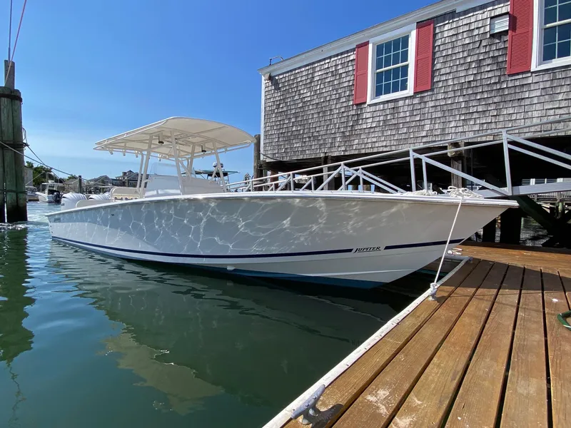 The Image of 2004 Jupiter 31 FS boat in a workshop, surrounded by flags and equipment. - 0