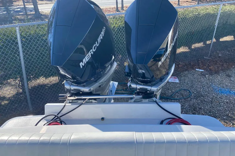 Slide: The Image of 2004 Jupiter 31 FS boat with dual Mercury outboard engines, parked near a chain-link fence. - 22