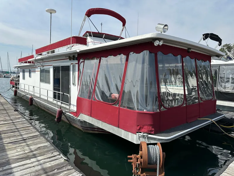 Slide: The Image of 1985 Sumerset 14x60 houseboat with red accents docked at marina. - 0