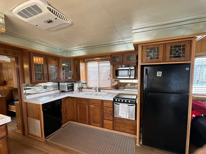 Slide: The Image of 1985 Sumerset 14x60 houseboat kitchen with wooden cabinets and modern appliances. - 4