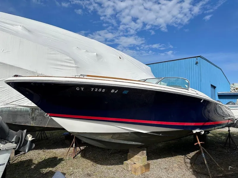 Slide: The Image of 2003 Chris-Craft 28' Corsair boat on stands, blue hull, red stripe, outdoor storage. - 0