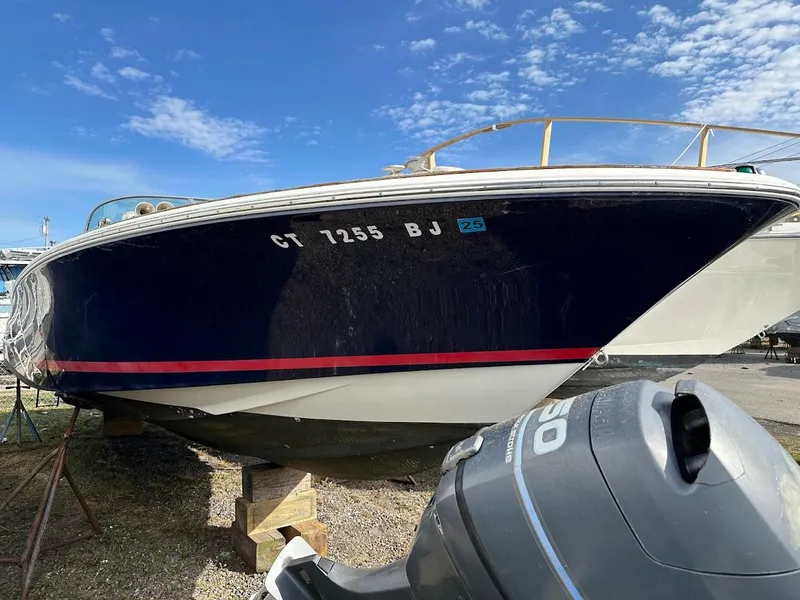 Slide: The Image of 2003 Chris-Craft 28' Corsair boat on land, blue hull, outboard motor visible. - 1