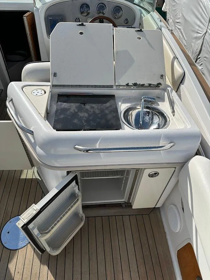 Slide: The Image of 2003 Chris-Craft 28' Corsair boat kitchenette with sink, stove, and mini-fridge on deck. - 14