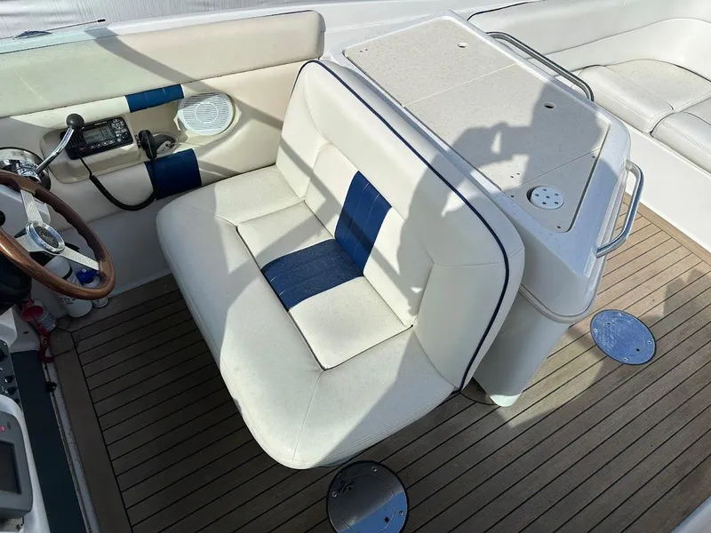 Slide: The Image of 2003 Chris-Craft 28' Corsair boat interior with white and blue seating on wooden deck. - 17