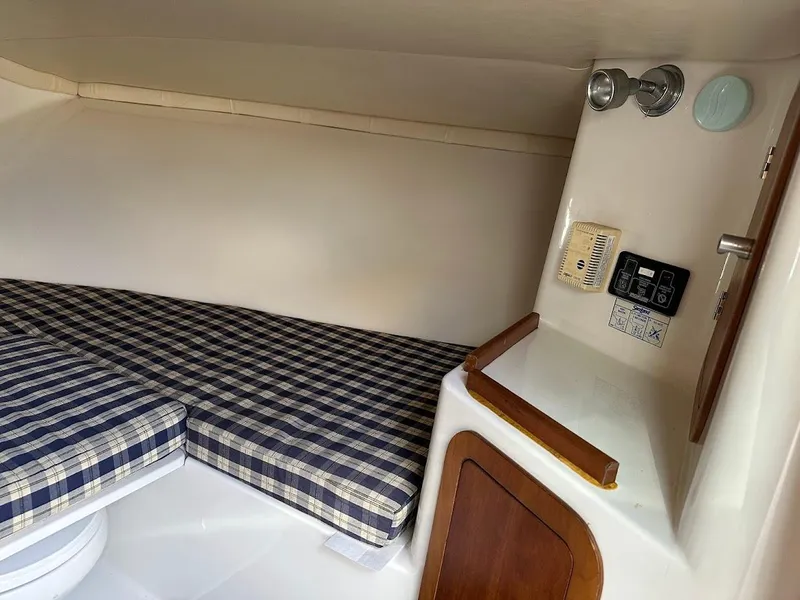 Slide: The Image of 2003 Chris-Craft 28' Corsair cabin interior with plaid bedding and wooden accents. - 26