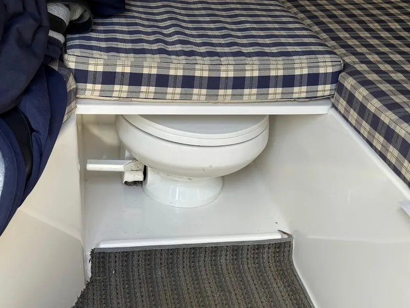 Slide: The Image of 2003 Chris-Craft 28' Corsair interior with plaid cushions and a compact marine toilet. - 28