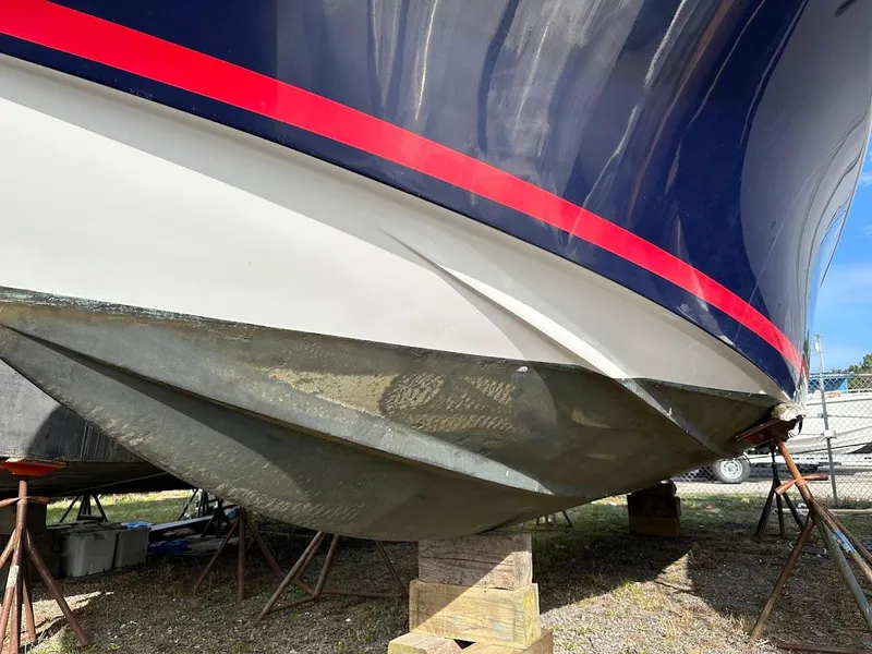 Slide: The Image of 2003 Chris-Craft 28' Corsair boat hull with red stripe, on stands outdoors. - 29