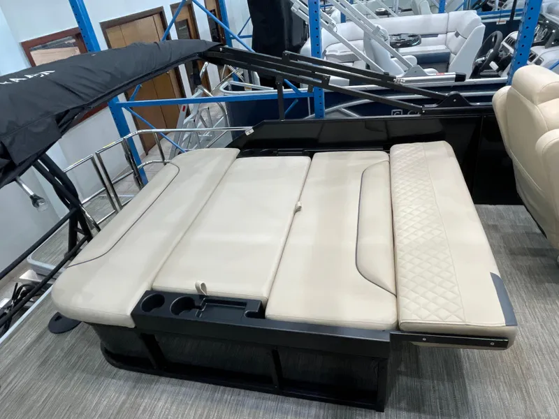 Slide: The Image of 2025 Godfrey SW2286SFLC Tritoon with beige seating and cup holders, showcased indoors. - 15