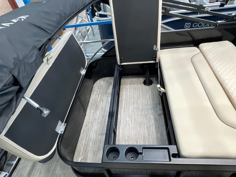 Slide: The Image of 2025 Godfrey SW2286SFLC Tritoon interior with open storage compartments and beige seating. - 17
