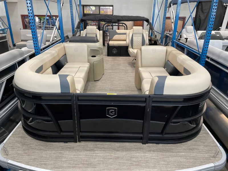 Slide: The Image of 2025 Godfrey SW2286SFLC Tritoon with beige seating and black exterior in showroom. - 2
