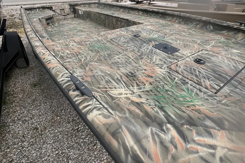 Slide: The Image of 2025 SeaArk 1960 Slayer Pro boat with camouflage design on gravel surface. - 6