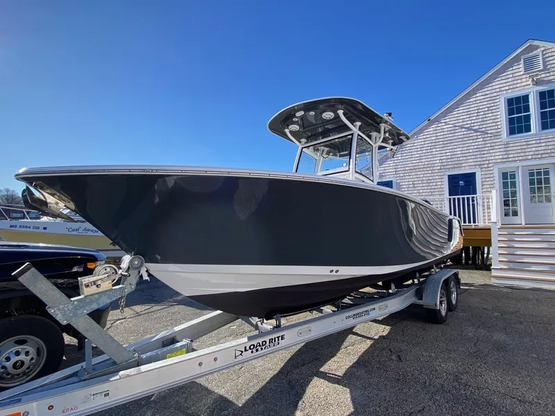 Slide: The Image of 2020 Sportsman Heritage 251 Center Console boat on trailer, parked near a building. - 1