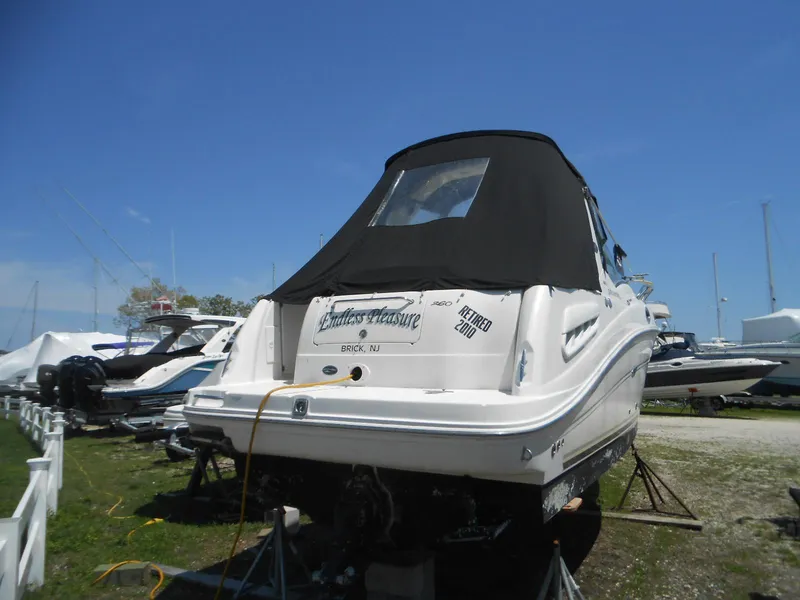 Slide: The Image of 2008 Sea Ray 260 Sundancer boat on stands, covered, in a marina setting. - 2