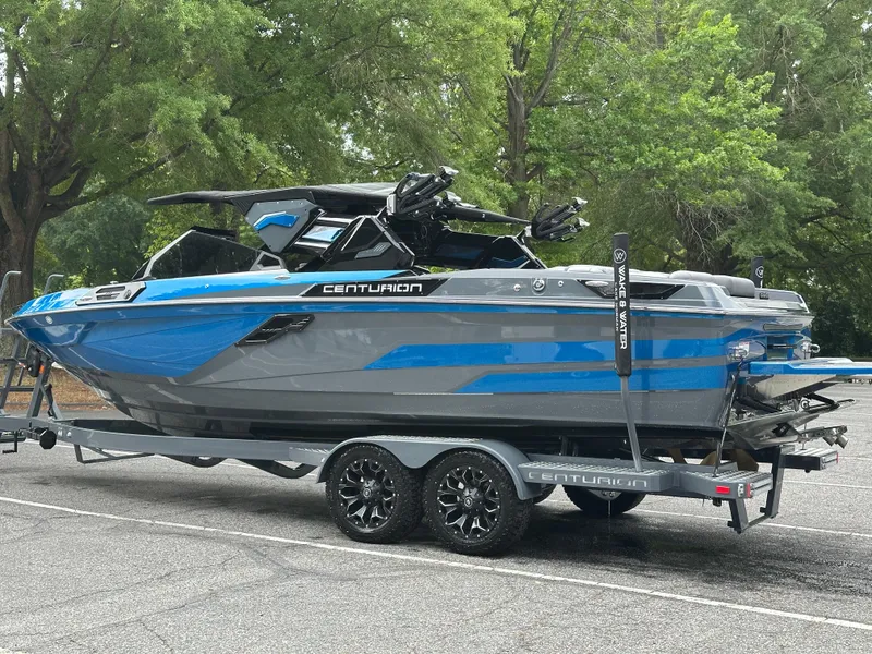 Slide: The Image of 2025 Centurion Ri245 boat on trailer, blue and gray design, parked outdoors. - 20