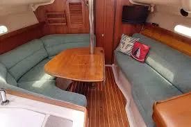 Slide: The Image of 1996 Catalina C-320 yacht interior with wooden table, teal seating, and nautical decor. - 4
