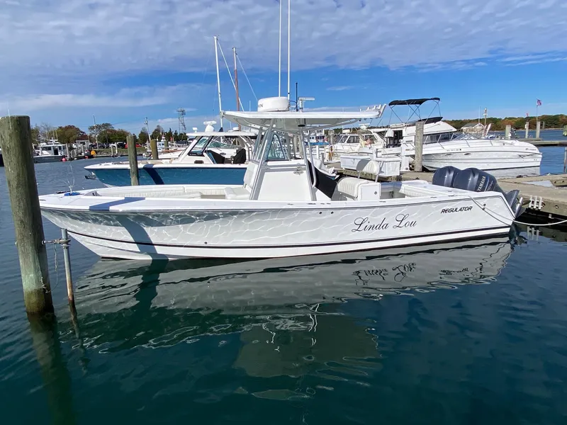 Slide: The Image of 2007 Regulator 29 Forward Seating boat docked in a marina, clear sky reflection. - 5