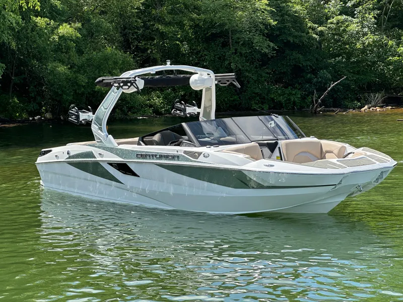 Slide: The Image of 2025 Centurion Fe23 boat on calm water, surrounded by lush greenery. - 2