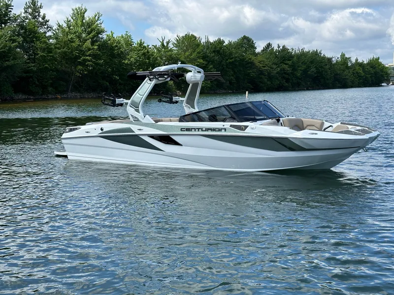 Slide: The Image of 2025 Centurion Fe23 boat on a serene lake with lush green trees. - 6