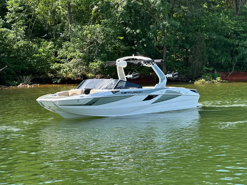 Slide: The Image of 2025 Centurion Fe23 boat cruising on a serene lake with lush green trees. - 7