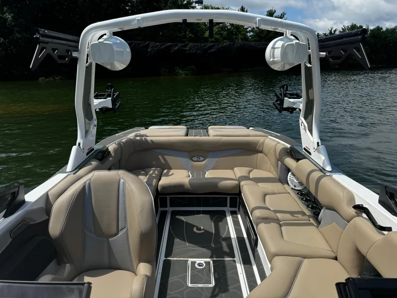 Slide: The Image of 2025 Centurion Fe23 boat interior with beige seating, on a calm lake. - 9