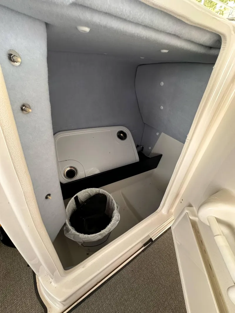 Slide: The Image of 2020 Yamaha Boats AR240 storage compartment with trash bin and carpeted interior. - 13