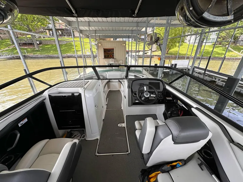 Slide: The Image of 2020 Yamaha AR240 boat interior with steering wheel, seating, and dock view. - 14