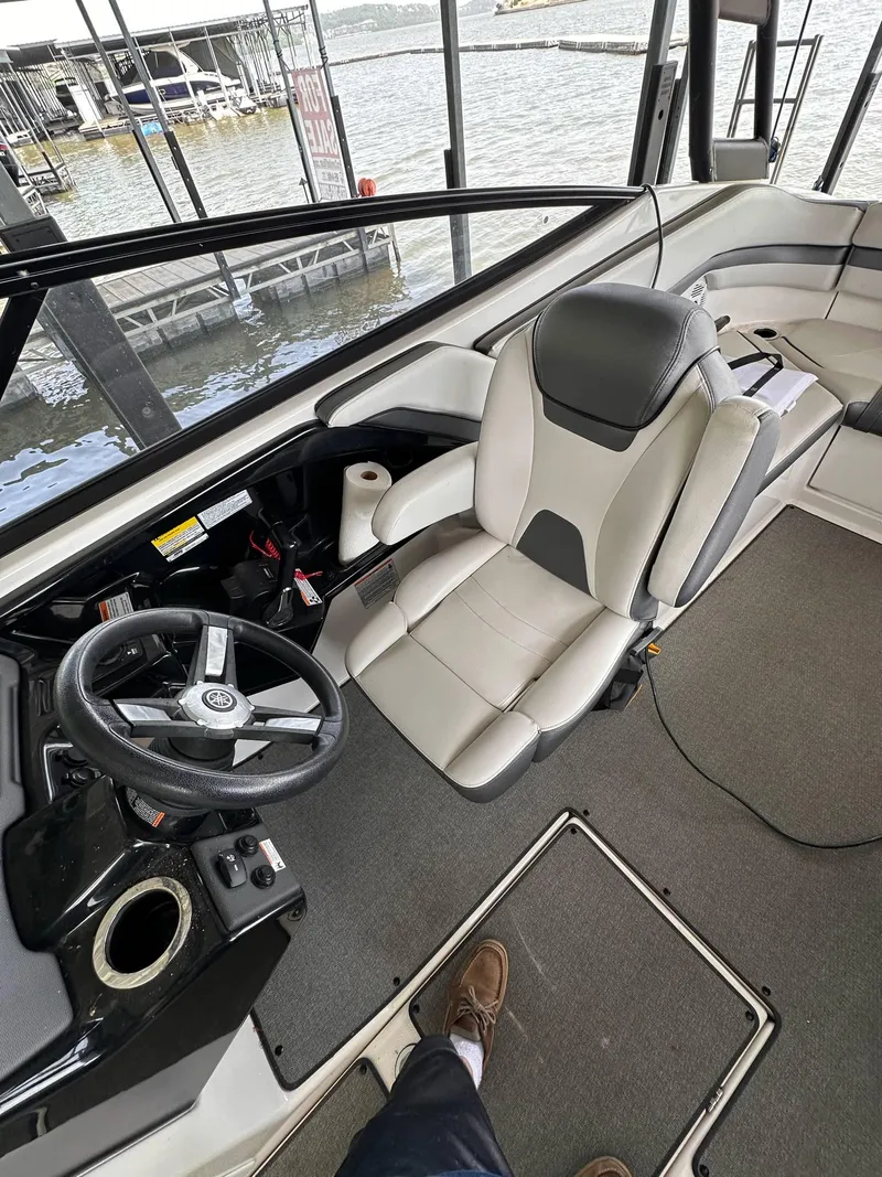 Slide: The Image of 2020 Yamaha Boats AR240 interior with steering wheel and seating, docked by the water. - 15