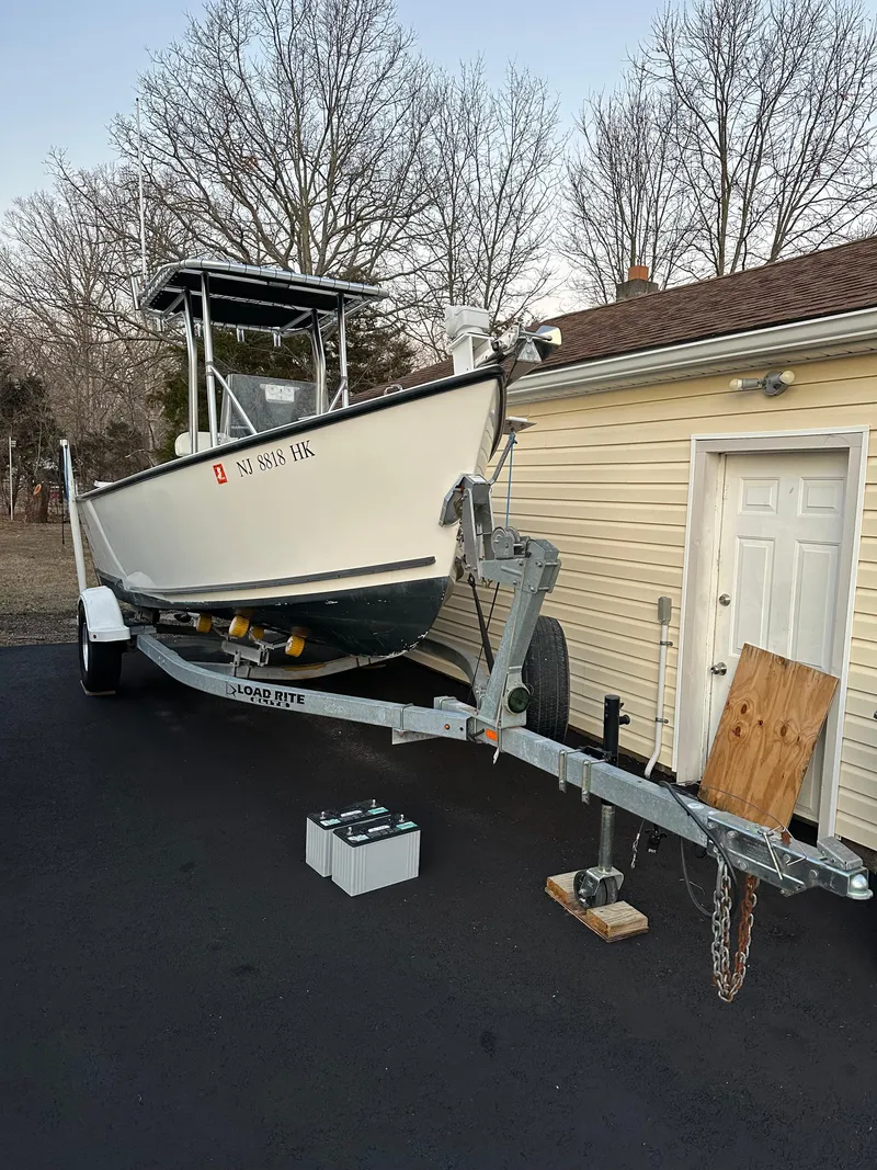 Slide: The Image of 2015 Allied 17 Explorer boat on trailer beside a garage, with trees in the background. - 2